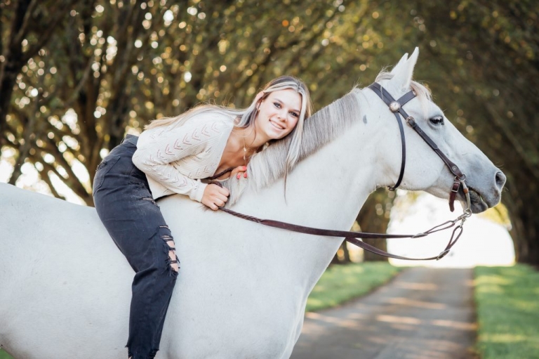 High School Senior posing for portraits on a white horse in Loudoun County Virginia